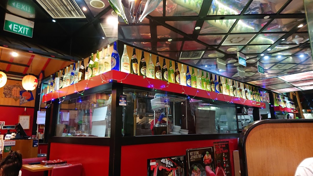 Vibrant interior of Tonkotsu Kazan Ramen, featuring a decorated counter, seating, and kitchen view.