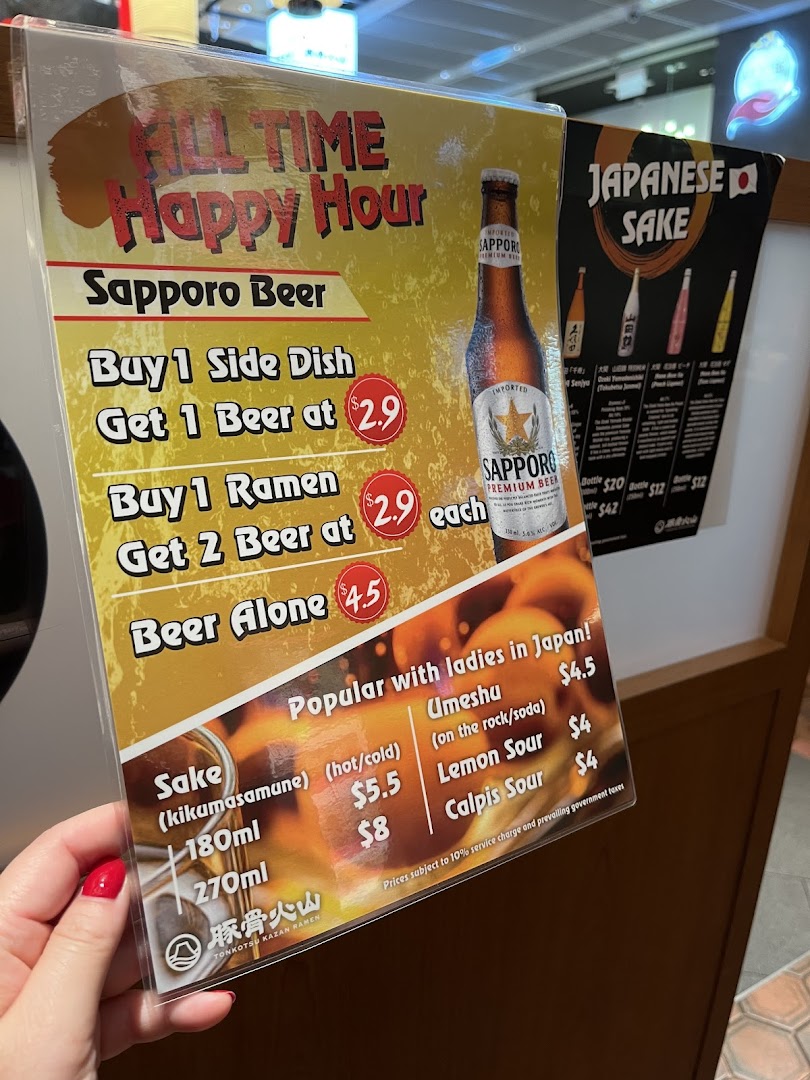 A menu board displaying happy hour deals for Sapporo beer and other Japanese drinks.