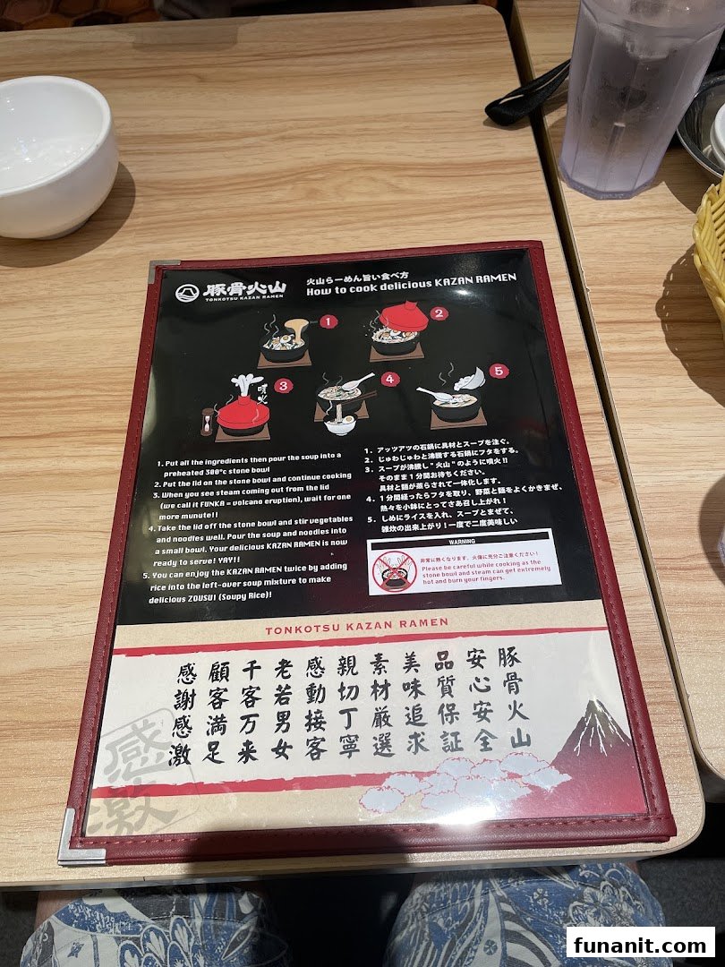 A laminated instruction sheet detailing how to enjoy Tonkotsu Kazan Ramen, placed on a wooden table.