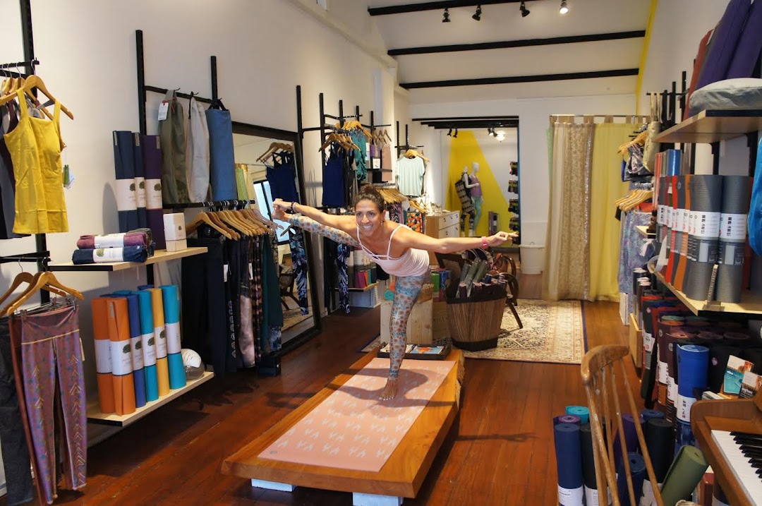 A woman in a yoga pose inside a retail shop featuring yoga apparel and accessories.