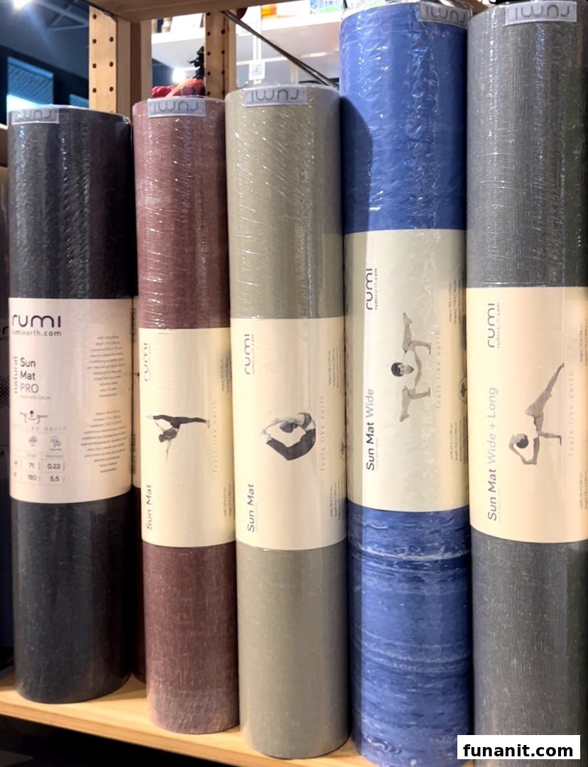 A display of colorful, rolled-up Rumi yoga mats on a shelf at Touch The Toes.
