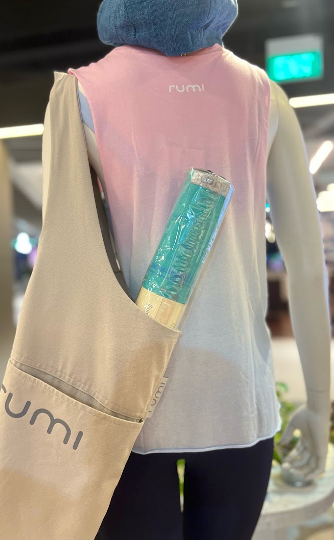 A mannequin displays activewear and a yoga mat in a Rumi bag, showcasing fitness essentials.