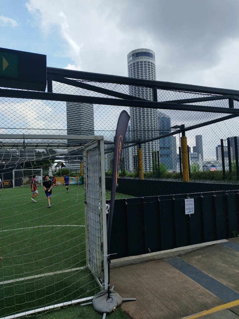 An outdoor rooftop football pitch at Funan with players and city skyline views.