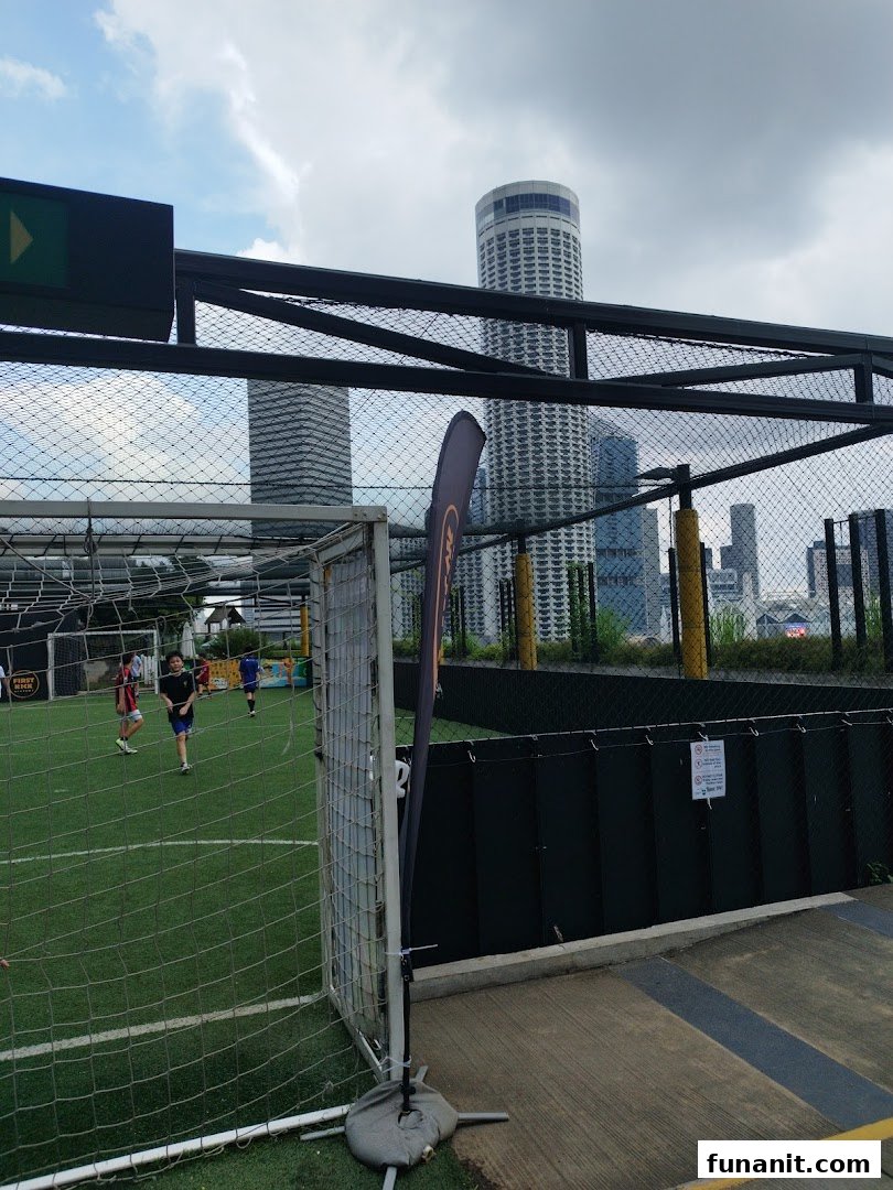An outdoor rooftop football pitch at Funan with players and city skyline views.