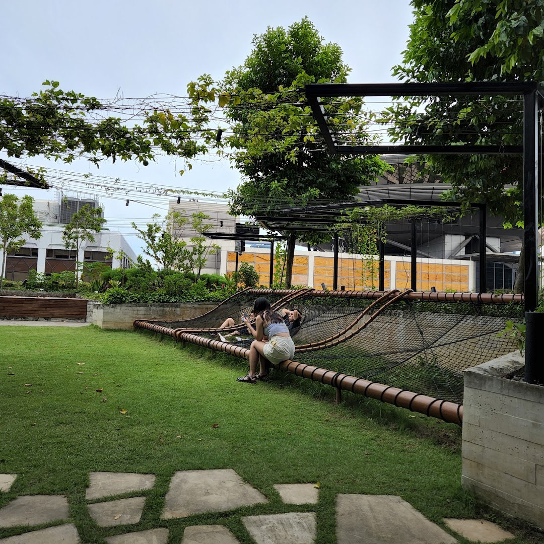 People relax on a unique net structure in a lush green outdoor space at Urban Farm Funan.