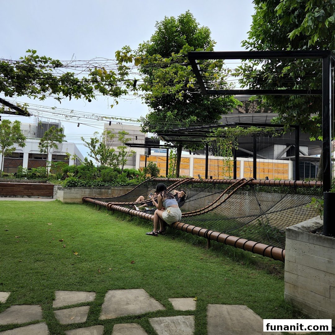 People relax on a unique net structure in a lush green outdoor space at Urban Farm Funan.