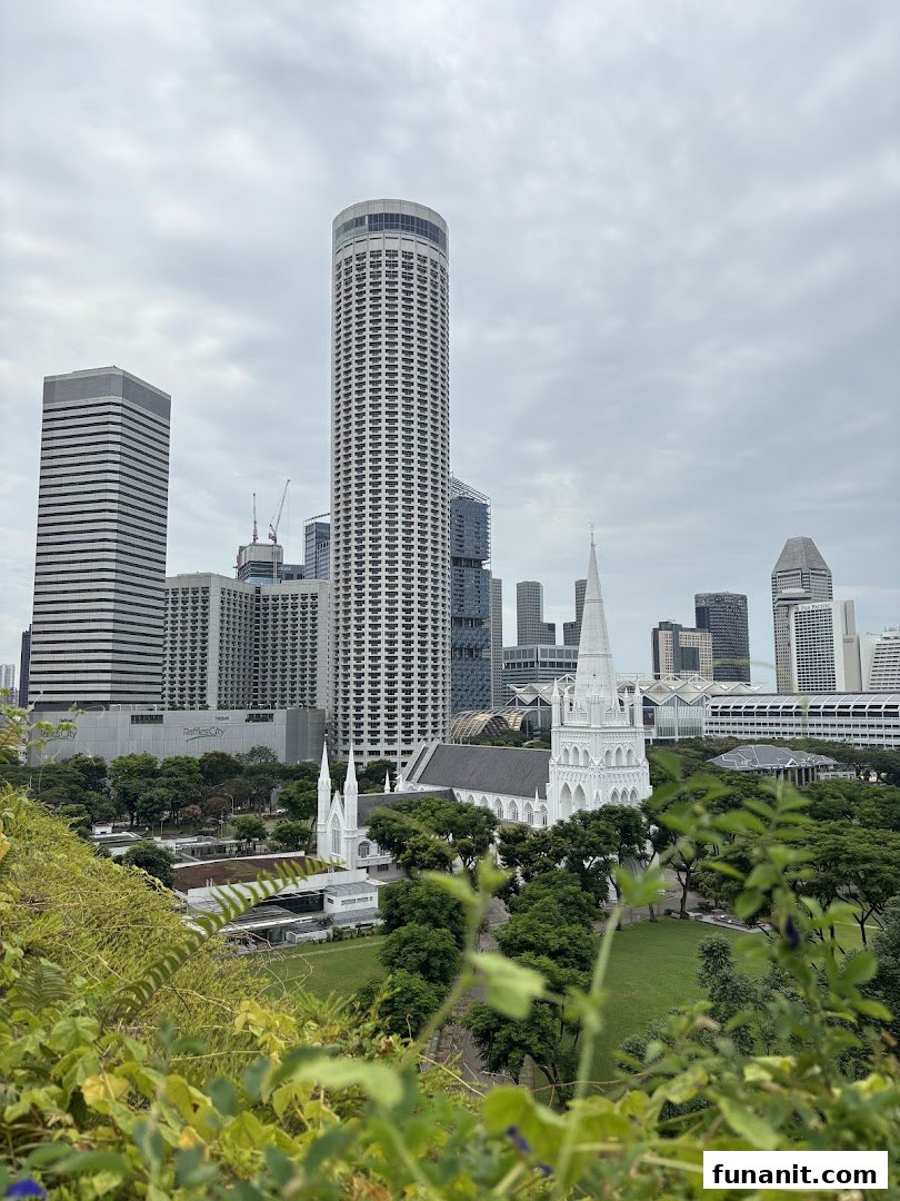 An aerial view of a city skyline featuring a white church and modern skyscrapers amidst lush greenery.
