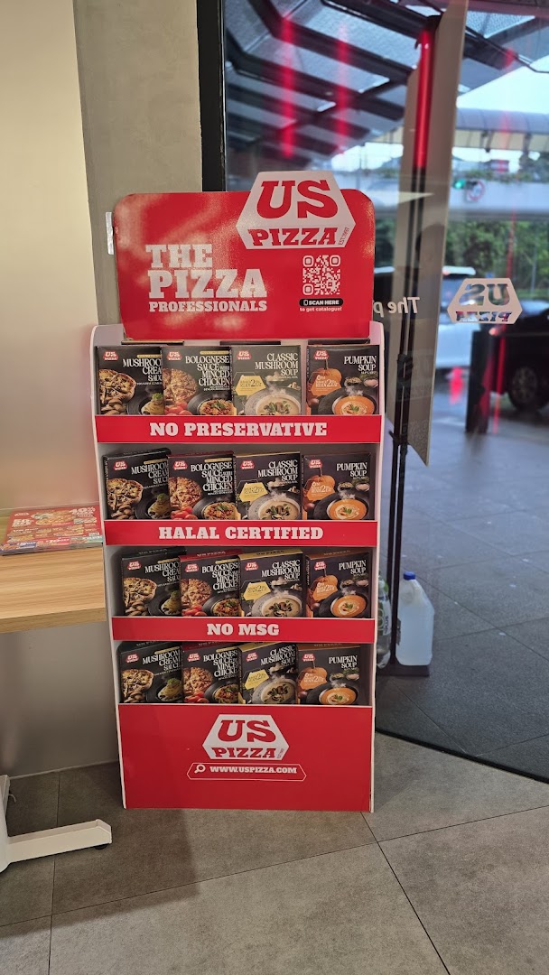 A US Pizza display stand showcasing various ready-to-eat sauces and soups near the shop entrance.