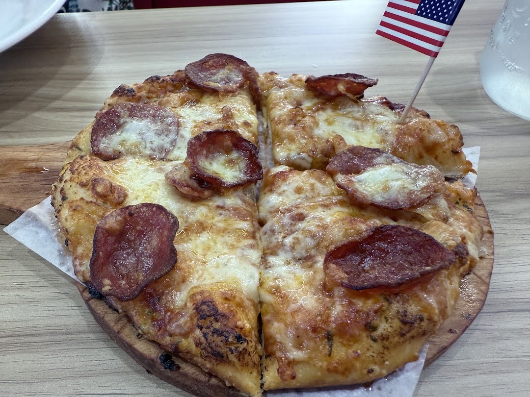 A delicious pepperoni pizza served on a wooden board with an American flag pick.