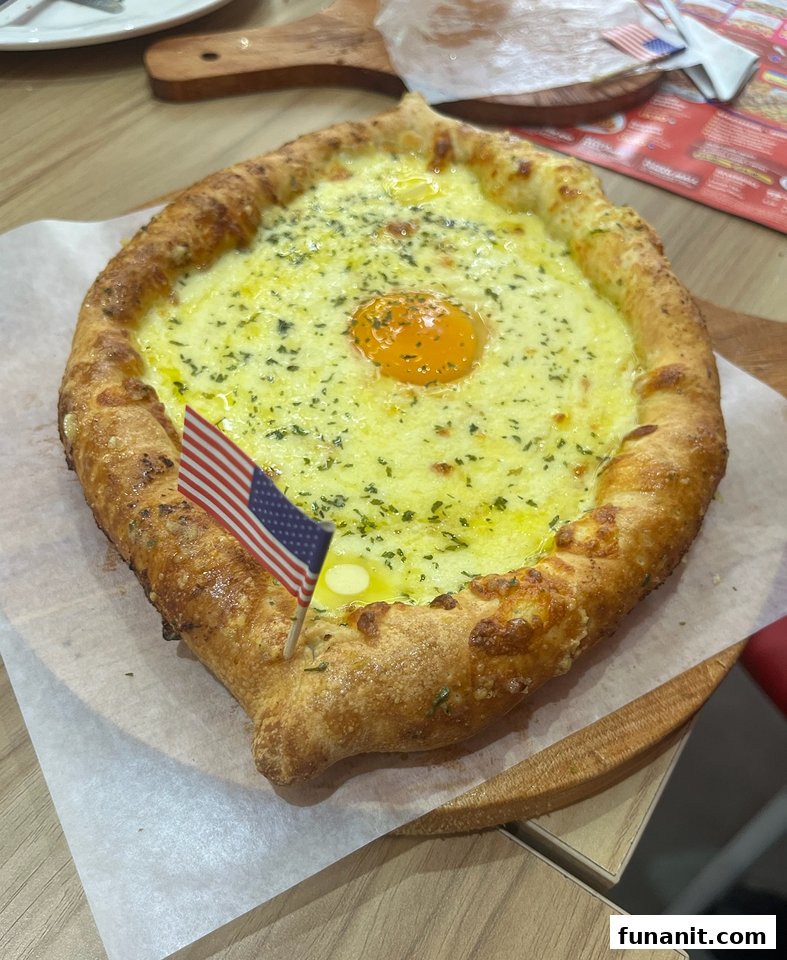 A cheesy, egg-topped pizza-like dish with an American flag pick, served on a wooden board.