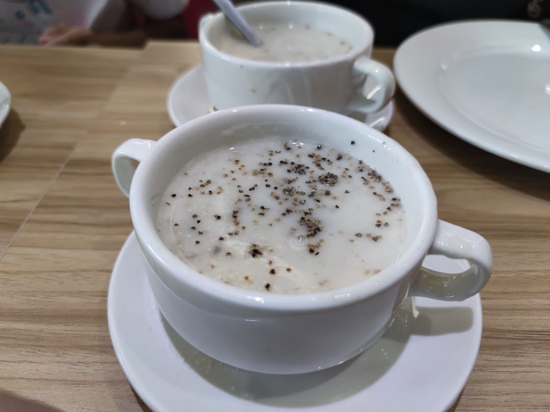 Two bowls of creamy soup with black pepper on a wooden table.