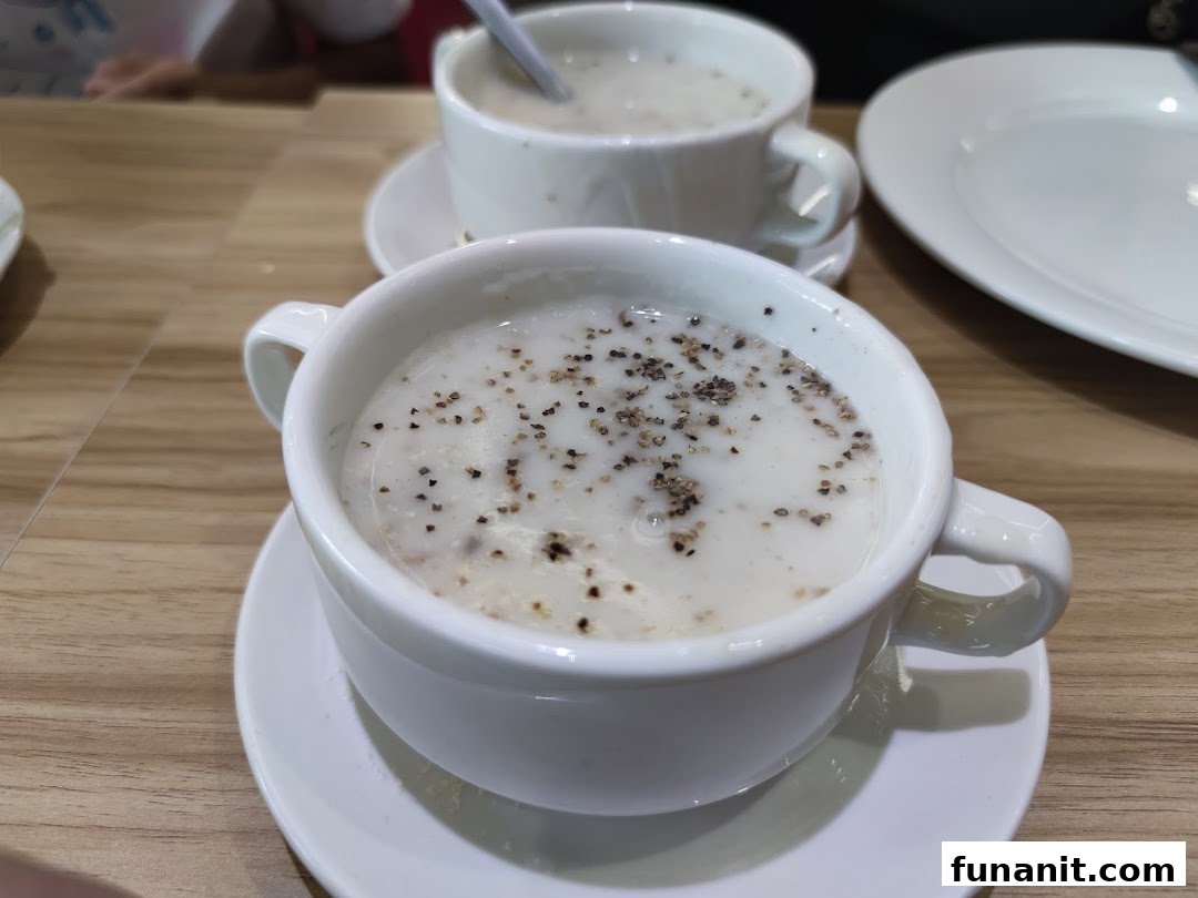Two bowls of creamy soup with black pepper on a wooden table.