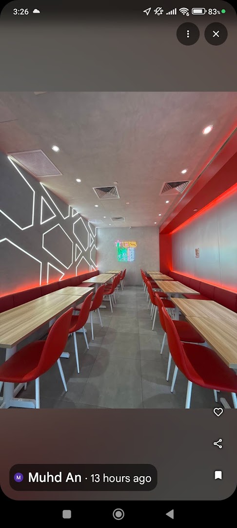 A vibrant interior view of US PIZZA, featuring modern red seating, wooden tables, and neon lighting.