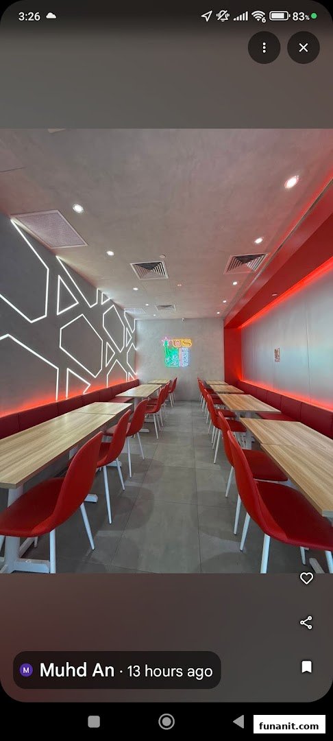A vibrant interior view of US PIZZA, featuring modern red seating, wooden tables, and neon lighting.