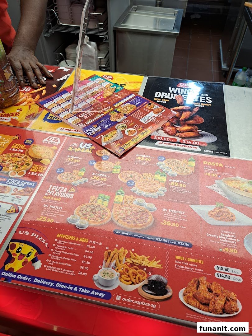 A counter display showcasing US Pizza's extensive menu, including pizzas, sides, wings, and pasta.