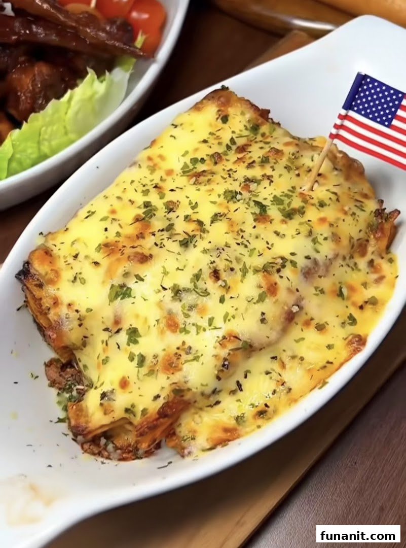 A cheesy baked dish, possibly lasagna, topped with herbs and an American flag pick.