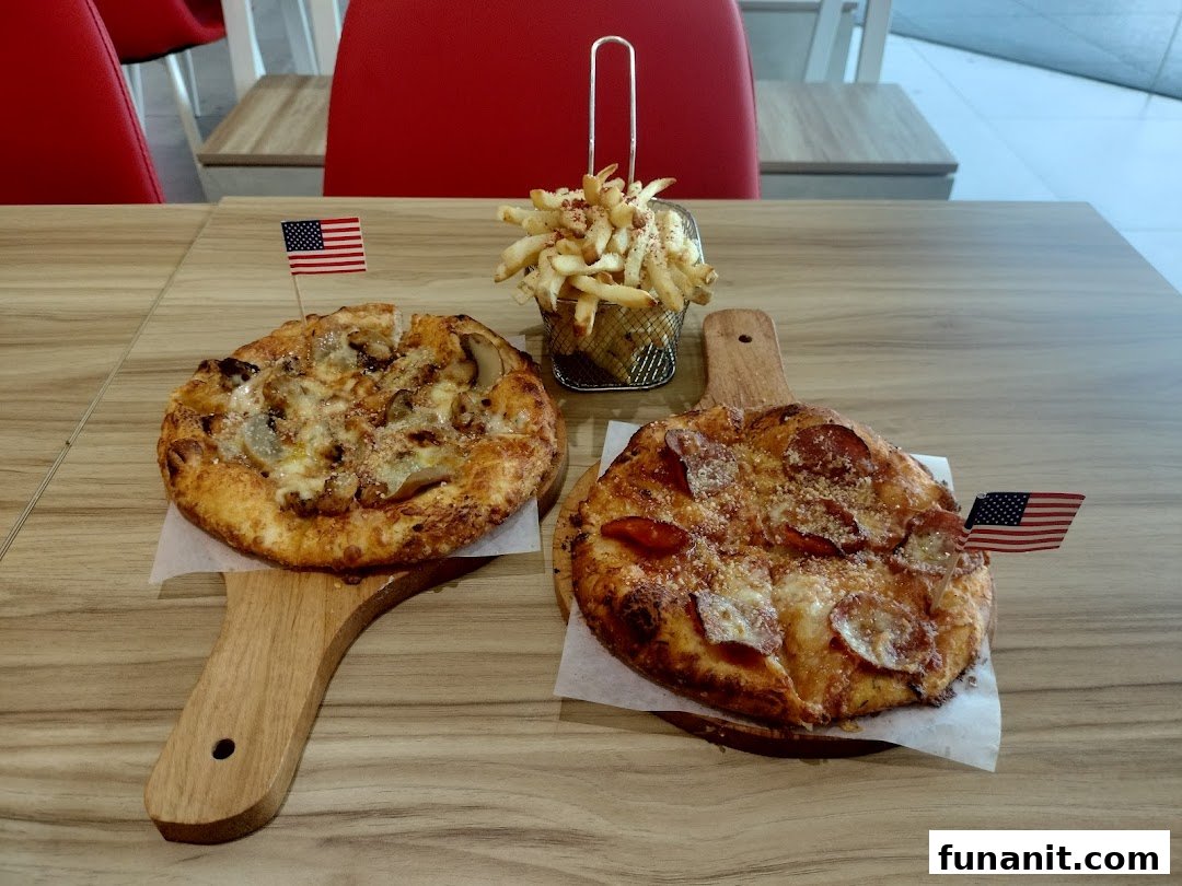 Two personal pizzas and a basket of fries served on a wooden table with American flag picks.