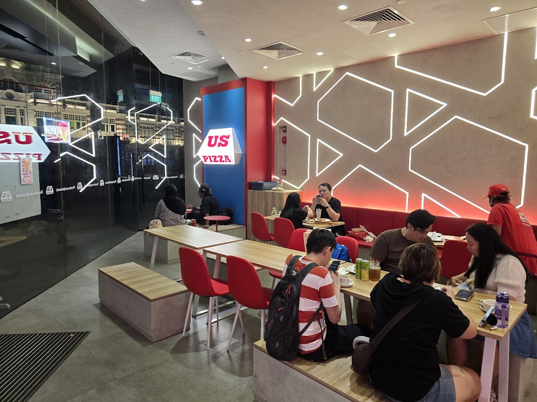 Diners enjoying meals inside US Pizza, featuring modern decor and comfortable seating.
