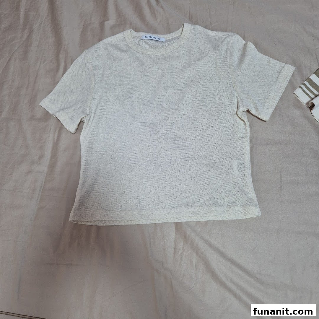 A light-colored, textured short-sleeved top from Wardrobemess, laid flat on a neutral surface.