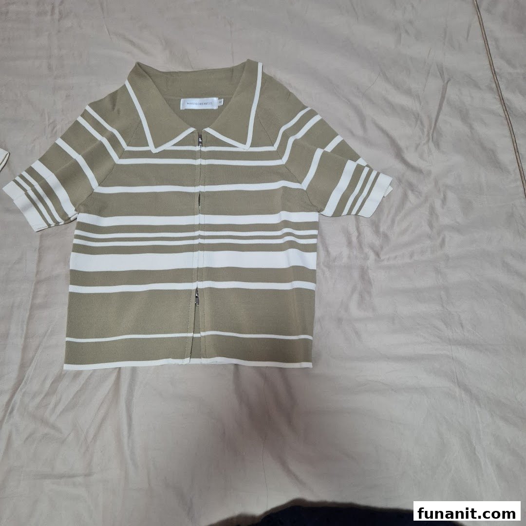 A beige and white striped knitted polo top with a full-length zipper, displayed on a light fabric.