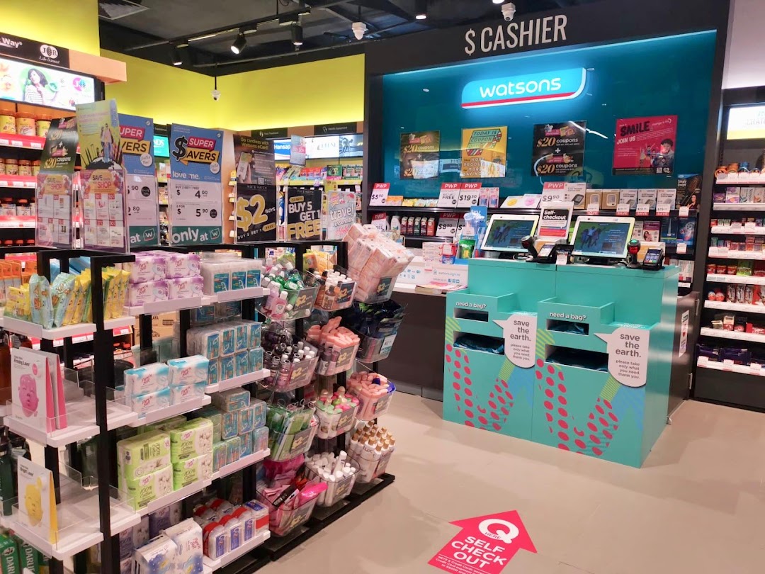 An interior view of a Watsons store, showcasing self-checkout counters and various health and beauty products on display.