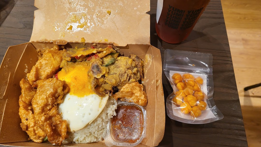 A delicious takeaway meal box featuring rice, fried chicken, egg, and sauce, with a drink and snack.