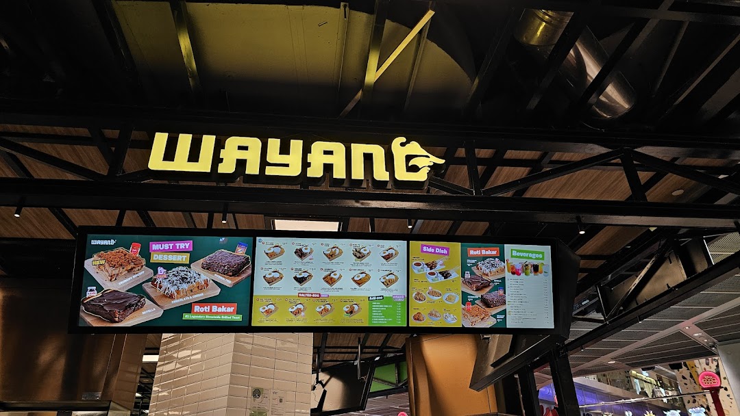 The Wayang Funan shop front featuring its bright yellow logo and digital menu boards displaying various food and beverage options.