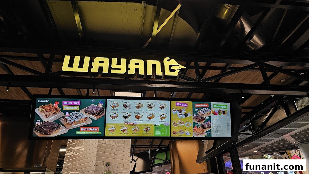 The Wayang Funan shop front featuring its bright yellow logo and digital menu boards displaying various food and beverage options.