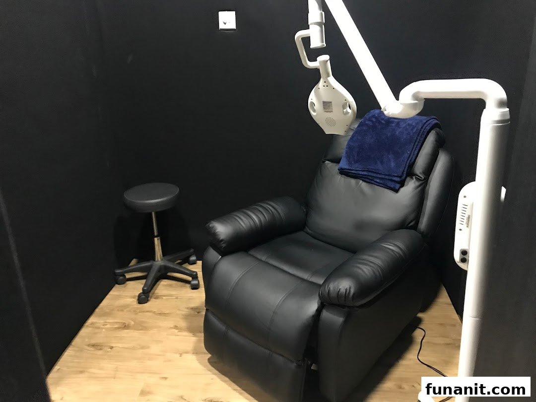A comfortable black recliner chair with a blue blanket and professional teeth whitening equipment in a private room.
