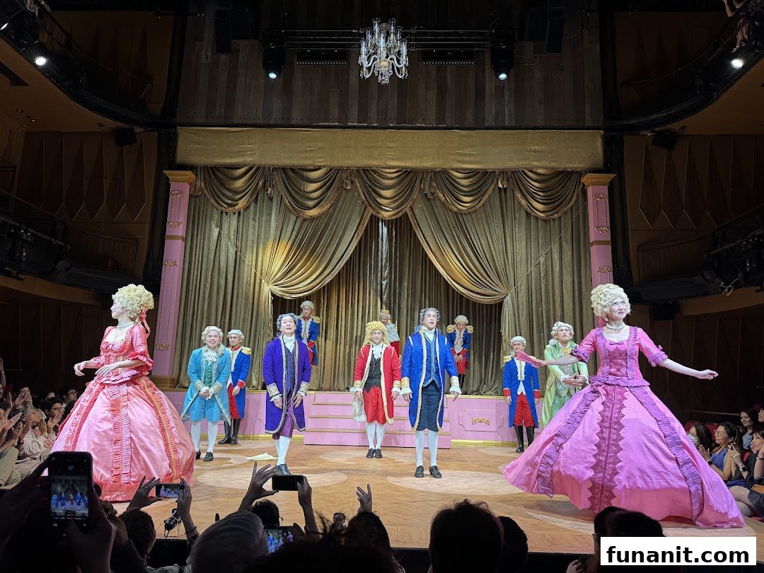Performers in elaborate 18th-century costumes on stage at Wild Rice Funan, with an audience watching.
