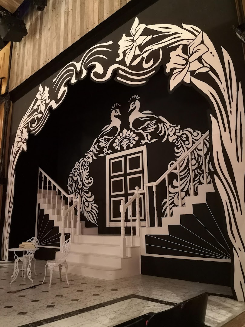 A dramatic black and white interior featuring peacock murals, a grand staircase, and elegant furniture.
