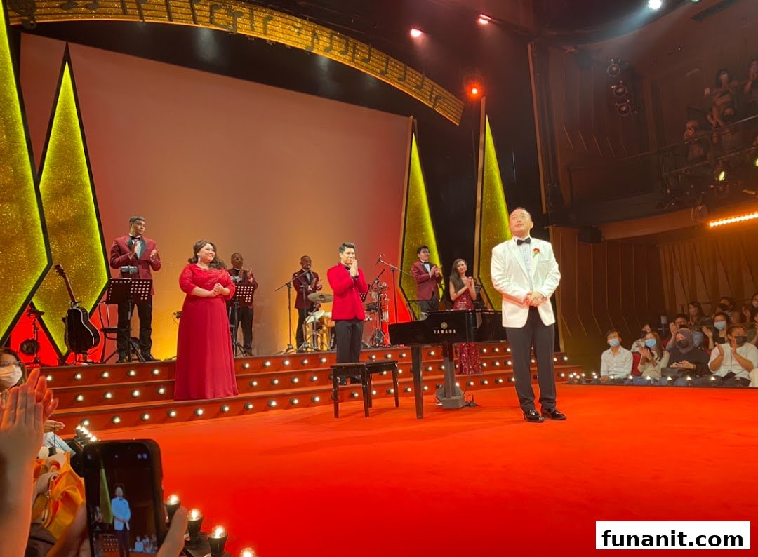 A vibrant stage performance featuring singers, musicians, and a grand piano, with an audience watching.