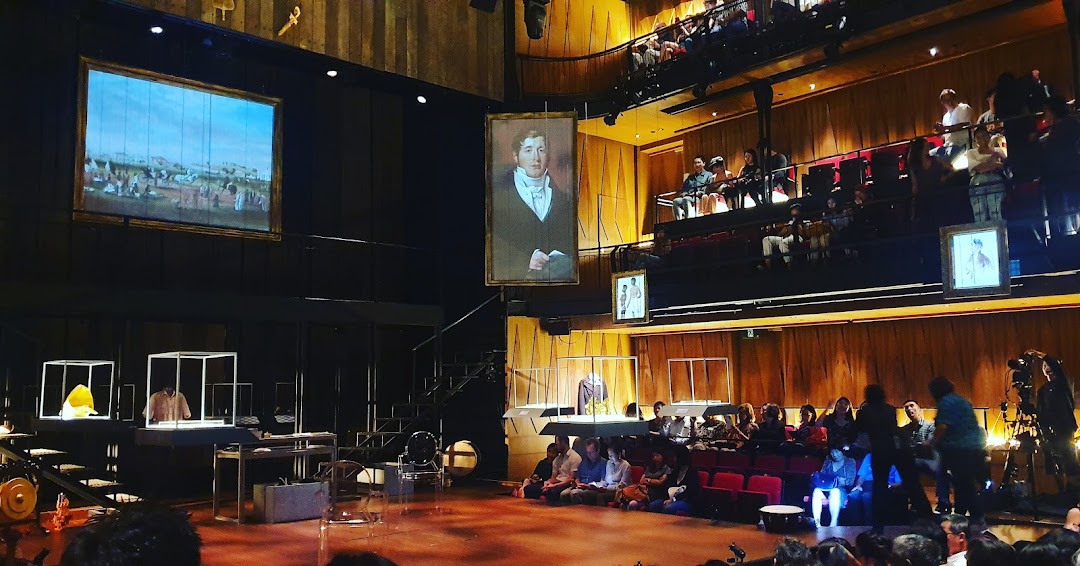 An audience watches a theatrical performance on stage at Wild Rice Funan, featuring projections and unique props.