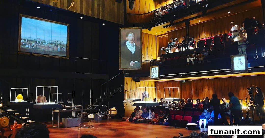 An audience watches a theatrical performance on stage at Wild Rice Funan, featuring projections and unique props.