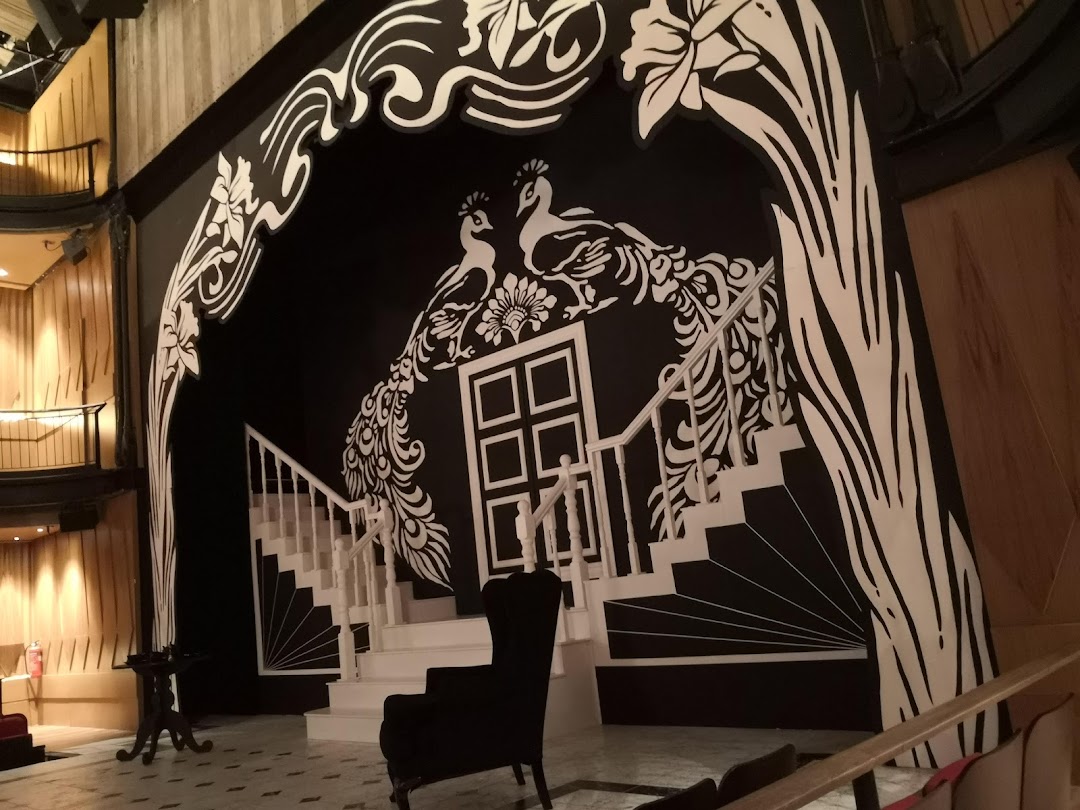 A striking black and white stage set featuring peacocks, a grand staircase, and ornate designs.