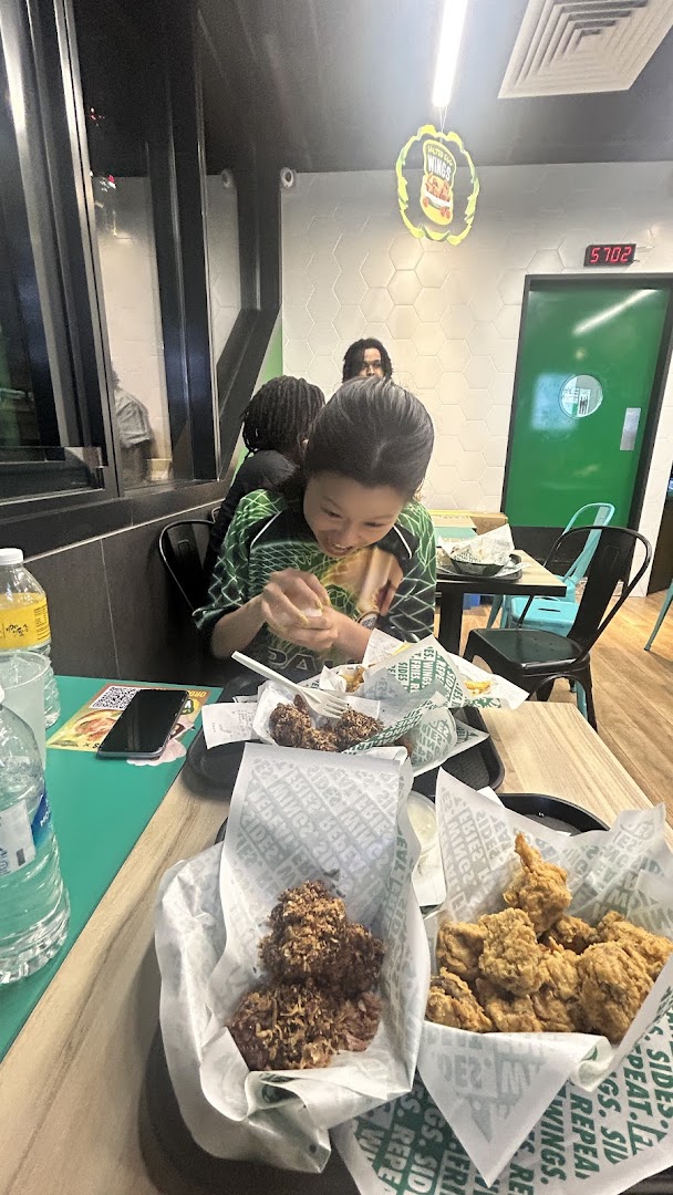 Customers enjoying various fried chicken items and drinks at Wingstop Funan, showcasing a lively dining experience.