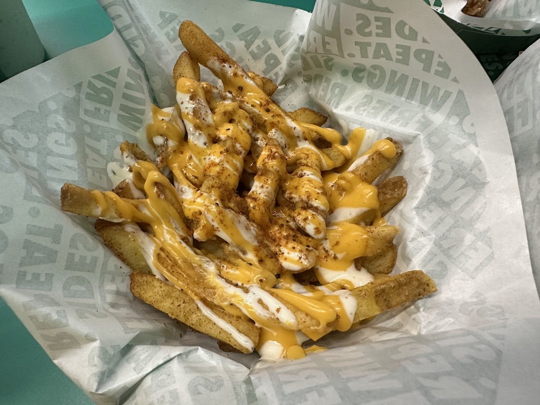 Close-up of Wingstop's seasoned fries generously topped with cheese and creamy sauces.