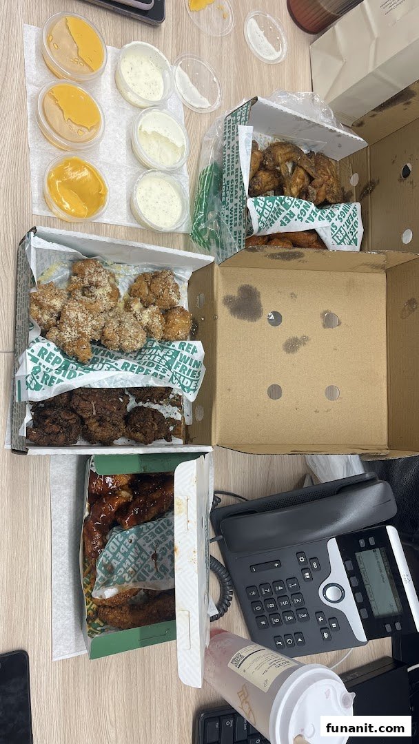 An overhead view of various Wingstop chicken wings, boneless bites, and dipping sauces in takeout boxes.