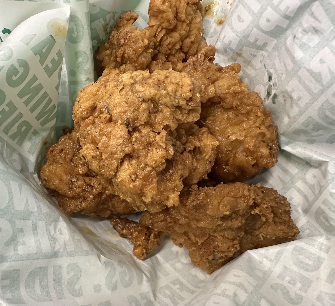 Close-up of crispy fried chicken pieces served in a Wingstop branded paper basket.