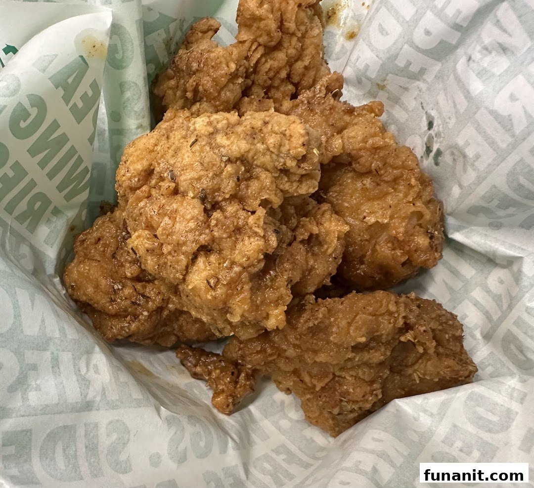 Close-up of crispy fried chicken pieces served in a Wingstop branded paper basket.