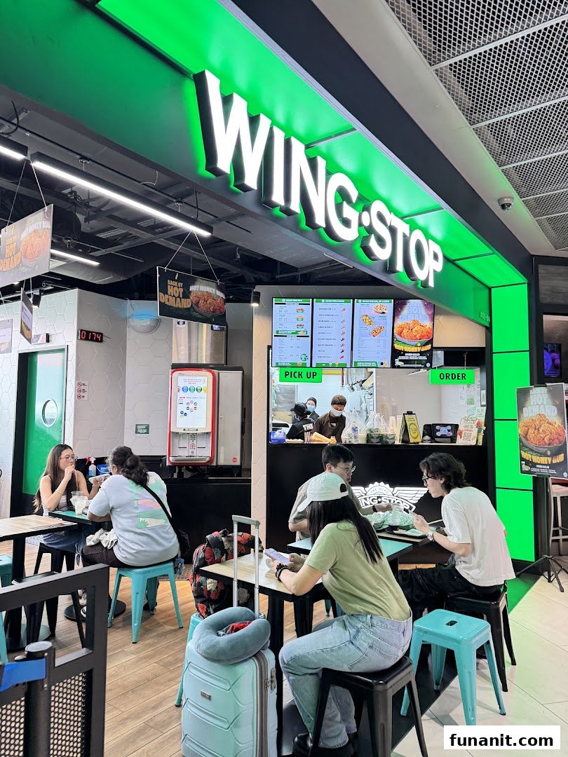 Customers enjoy delicious wings and sides at Wingstop Funan's vibrant, modern counter and dining area.