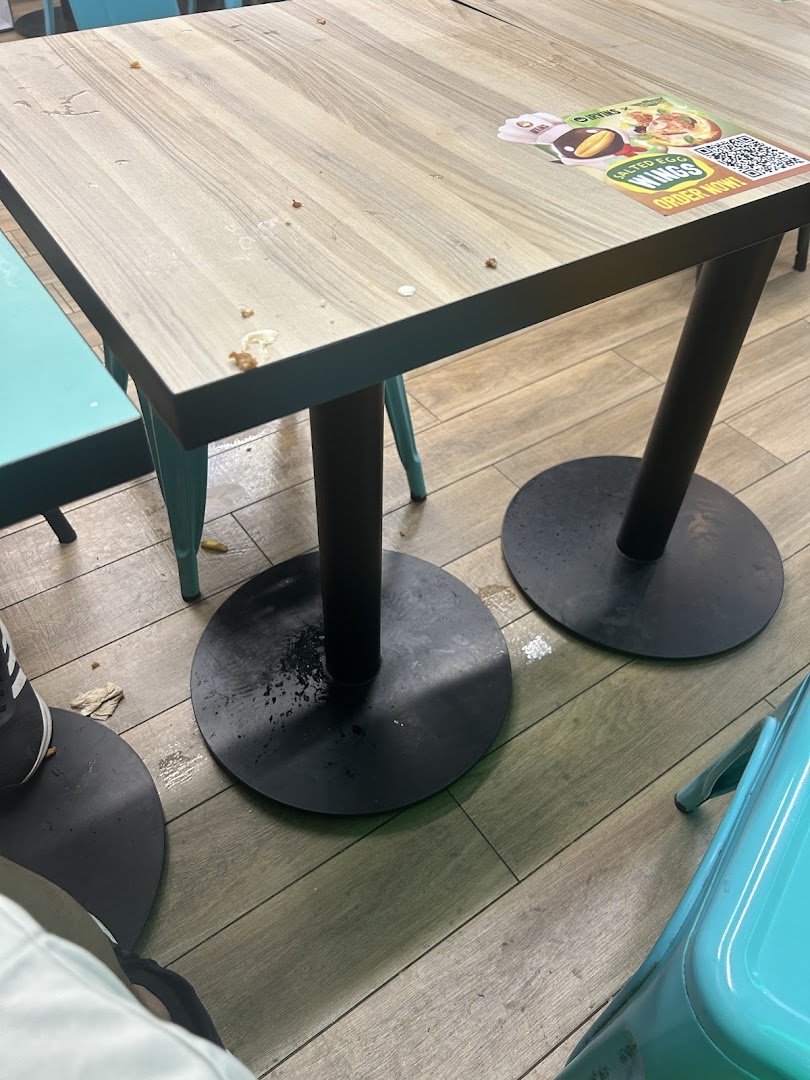 A wooden dining table with a promotional sticker and some debris, showing the restaurant's interior.