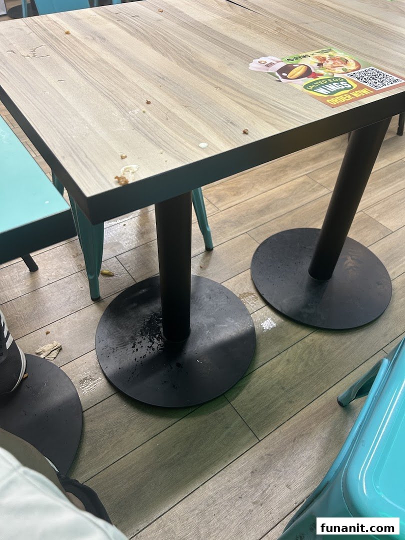 A wooden dining table with a promotional sticker and some debris, showing the restaurant's interior.