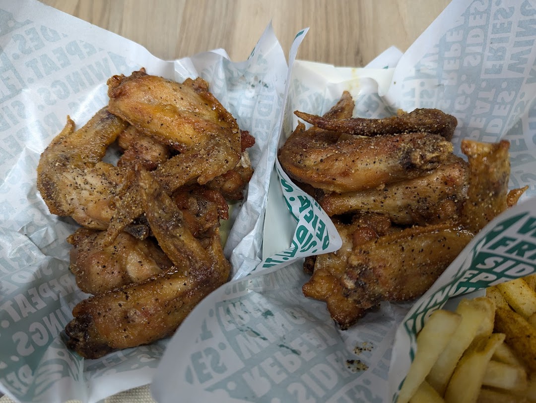 Close-up of delicious seasoned chicken wings and fries from Wingstop.