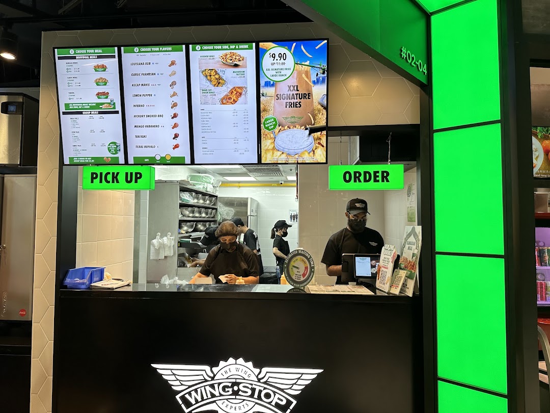Wingstop's vibrant counter with digital menus, showcasing staff and order/pickup points.