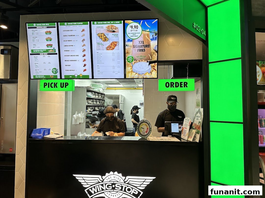 Wingstop's vibrant counter with digital menus, showcasing staff and order/pickup points.