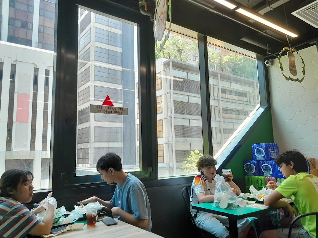 Customers enjoy their meals inside Wingstop Funan, featuring large windows with city views.