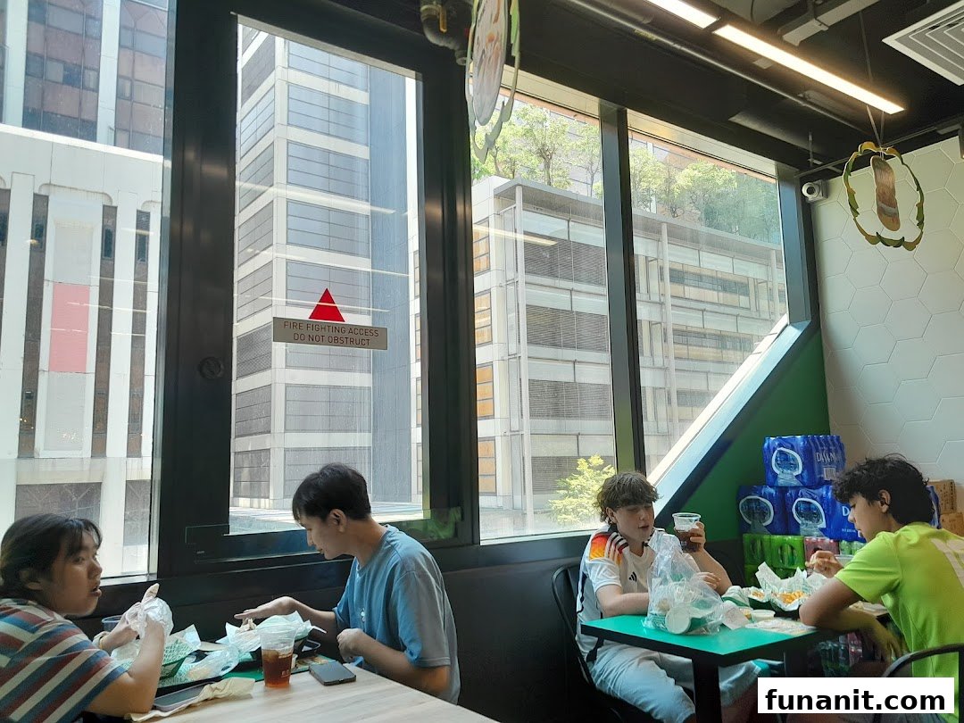 Customers enjoy their meals inside Wingstop Funan, featuring large windows with city views.