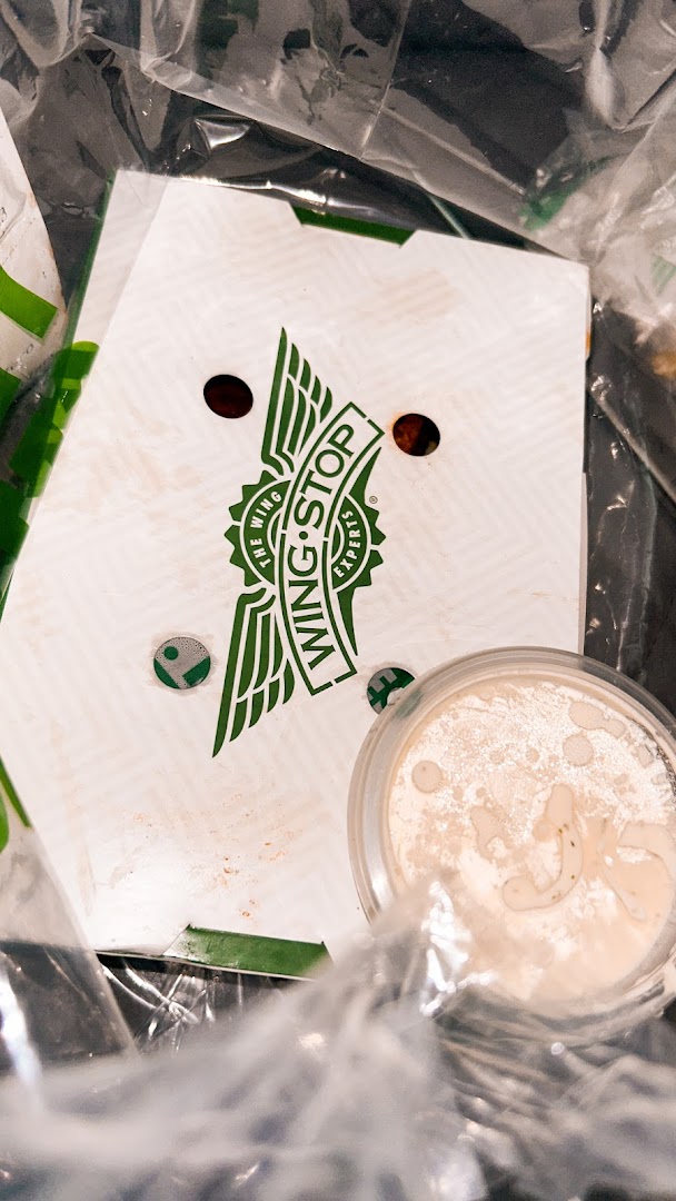 A Wingstop takeout box and drink cup are visible inside a plastic bag.