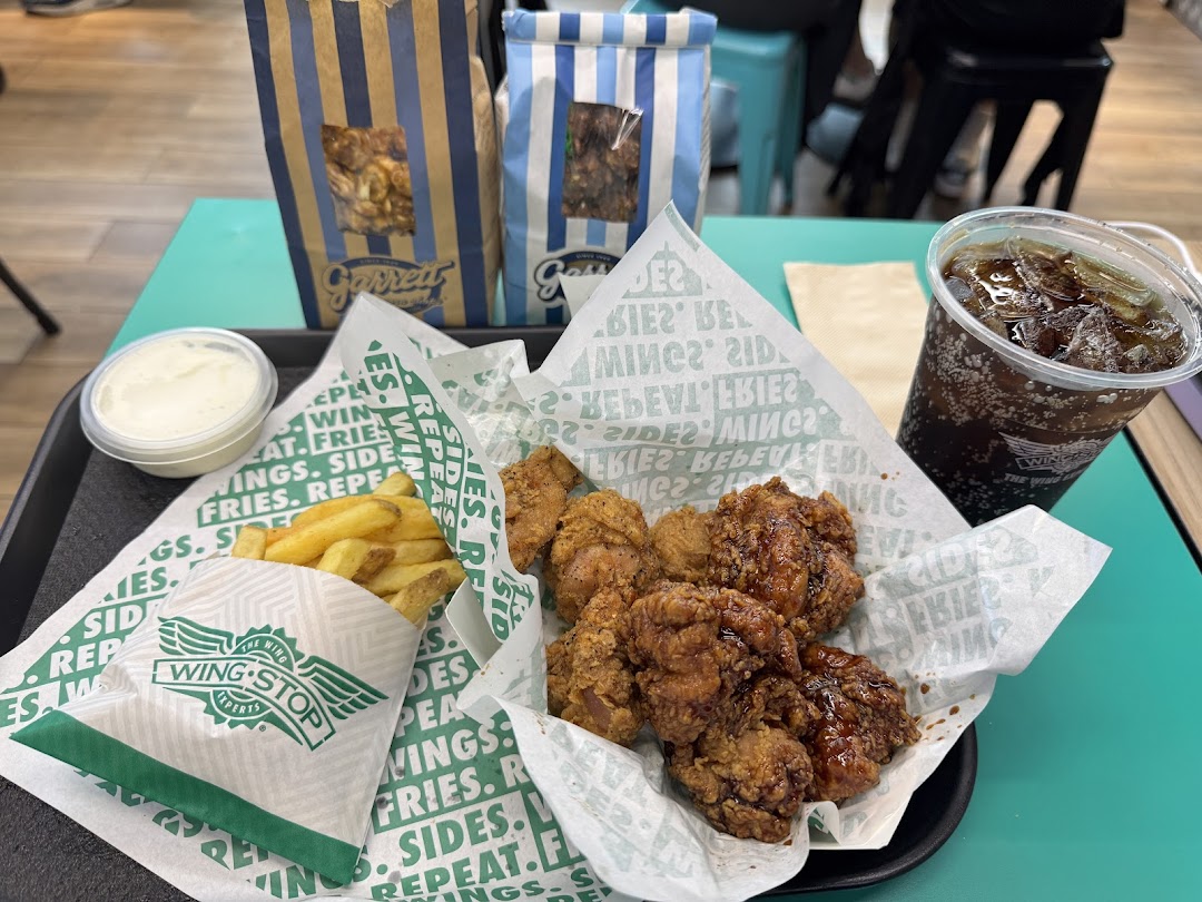 A delicious Wingstop meal featuring crispy chicken, golden fries, a refreshing drink, and creamy dip.